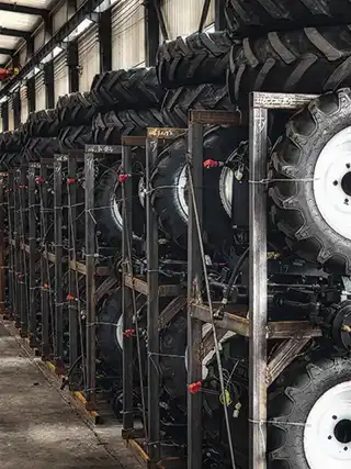 Lineup of farm tractors securely packed in reinforced iron frame crates (SKD packaging) ready for container loading and export.