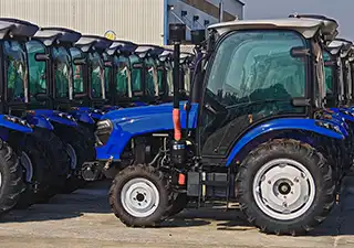 Row of blue XT series 50HP tractors with AC cabins lined up for final ISO-9001 quality inspection at the XT-AGRO factory.